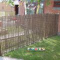 Woven Willow Screening along metal fence, green grass. Natural Play Area.